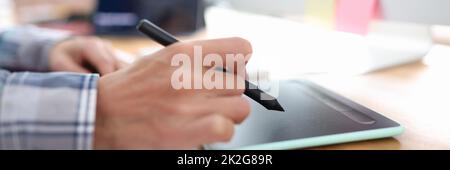 Stylus in hand from graphics tablet closeup Stock Photo