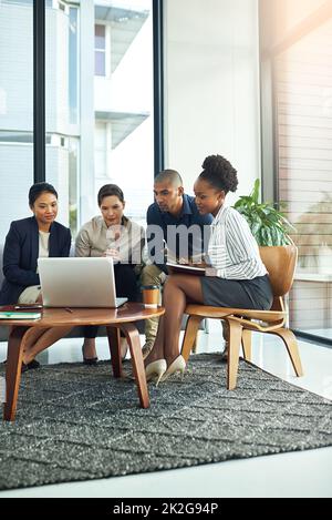 Everyones got their thinking cap on for this meeting. Shot of a group of businesspeople talking together over a laptop during a meeting. Stock Photo