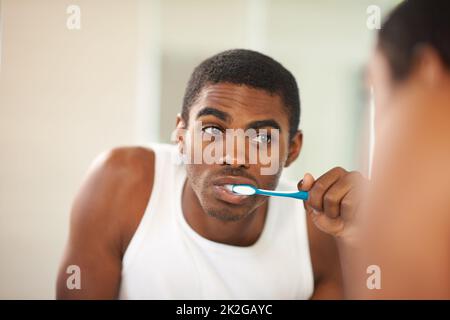 A brush a day keeps the decay away. A young man brushing his teeth. Stock Photo