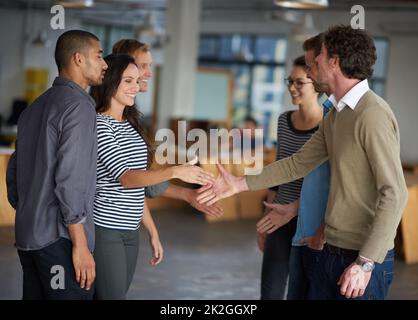Getting together to make things happen. Creative professionals greeting each other in an open office space. Stock Photo