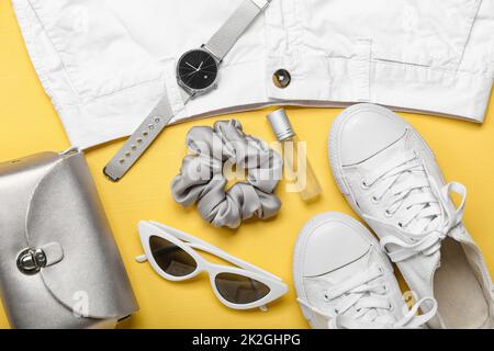 Stylish female clothes, silk scrunchy and different accessories on yellow background Stock Photo