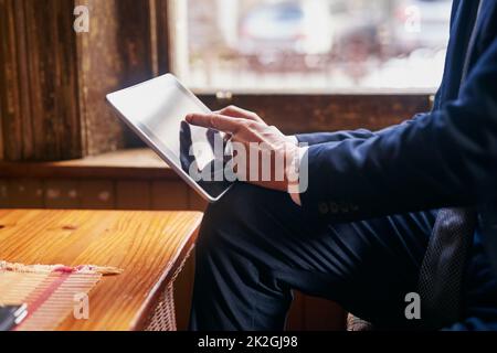 Taking a break from the office. Cropped shot of a well-dressed mature man using a digital tablet in a cafe after work. Stock Photo