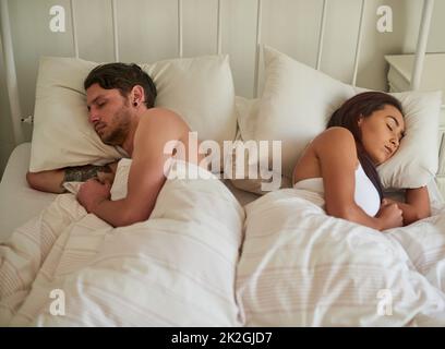 Never go to bed angry. Shot of a young couple sleeping on opposite sides of the bed at home. Stock Photo