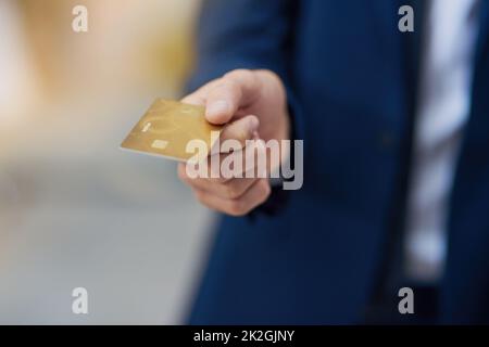 Paying by card. Cropped shot of an unrecognizable businessman holding out a credit card. Stock Photo