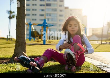 Ready to get her skate on. Shot of a young girl putting on her roller skates at the park. Stock Photo