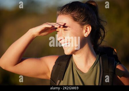 Theres still so much to see. Cropped shot of a young woman smiling while out hiking. Stock Photo