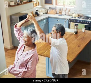 Getting in a bit of morning dancing. Shot of a cheerful elderly couple dancing in the kitchen together at home during the day. Stock Photo