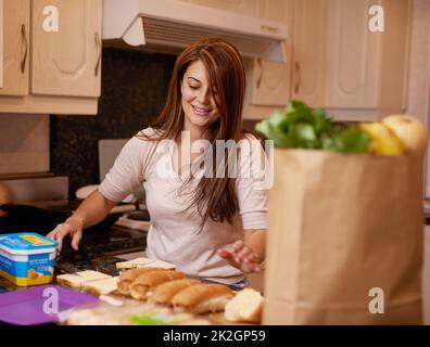 Assembling a nutritious meal. Shot of a young woman making sandwiches in a kitchen. Stock Photo