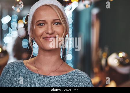 Im getting in touch with the christmas spirit. Portrait of a cheerful young woman wearing a festive hat at home during christmas time. Stock Photo