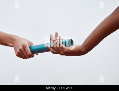 Nothing will stop us now. Shot of two athletes passing a baton during a relay race. Stock Photo