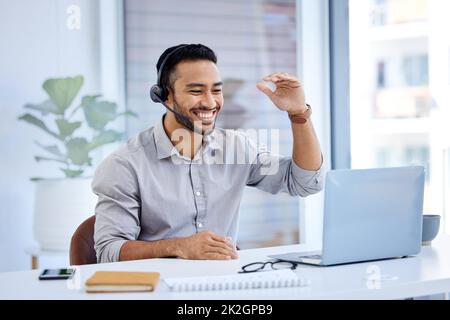 The definition of a top level salesman. Shot of a young businessman wearing a headset while working on a laptop in an office. Stock Photo