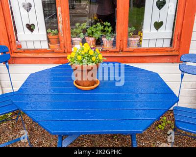 Angelsberg, Sweden - May 28, 2022: Blue table in front of the old cottage with white window shutter in the background Stock Photo