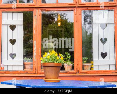 Angelsberg, Sweden - May 28, 2022: Blue wooden table with flowerpot, with raindrops, and reflection in the the glass Stock Photo