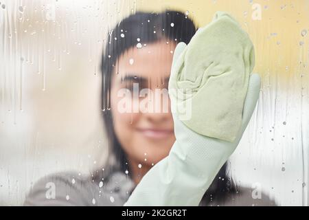 A little soap is all we need. Shot of a young woman washing windows at home. Stock Photo