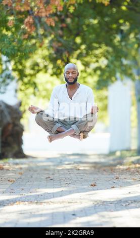 Yogas got him floating. Full length shot of a handsome young man levitating while meditating outside at the park. Stock Photo