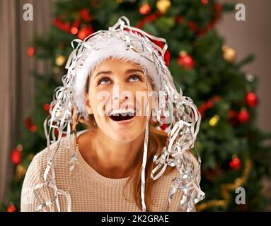 Its snowing. Shot of a beautiful young woman enjoying a playful moment with Christmas decorations. Stock Photo