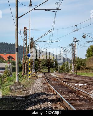 Empty railway tracks on a sunny summer day, in rural area, pillars with many electric cables around. Stock Photo