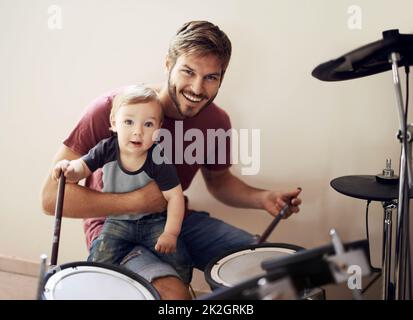 Father and son...rocking out together. A young father teaching his son to play the drums. Stock Photo