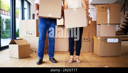 Boxes full of possessions, hearts full of priceless memories. Shot of an unrecognisable mature couple carrying boxes on moving day. Stock Photo