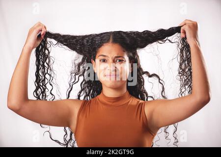Should I do something else with it. Shot of a young woman with long brown hair posing in the studio. Stock Photo