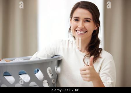Loving laundry day. Shot of a young woman doing laundry at home. Stock Photo