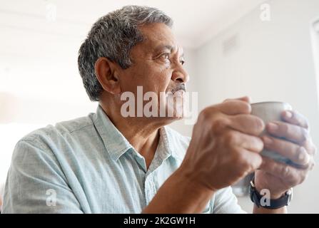 Thoughts over coffee. Shot of a senior man drinking coffee at home. Stock Photo