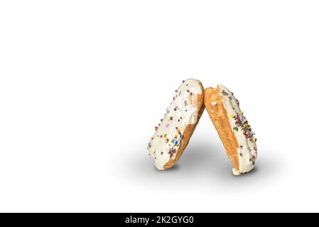 Two eclairs decorated with white chocolate icing and colorful baking sprinkles on a white background. Stock Photo