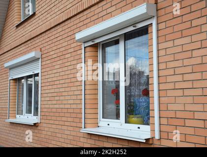 Rolling shutters house windows protection. Brick house with metal roller shutters on the windows Stock Photo