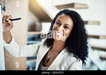 I dont just talk, I make it happen. Portrait of a young businesswoman writing notes on a white board during a brainstorming session at work. Stock Photo