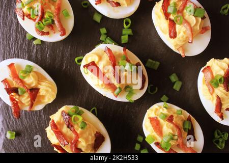 Stuffed Deviled Eggs witg bacon on black background Stock Photo