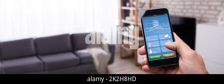 Man Using Smart Home Application On Mobile Phone Stock Photo