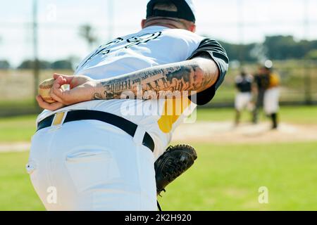 Hes one skillful pitcher. Cropped shot of an unrecognizable baseball player preparing to pitch a ball during a match on the field. Stock Photo