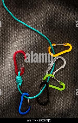 colourful carabiner accessories on a small turquoise rope with dramatic low key lighting. This tool is not for climbing Stock Photo