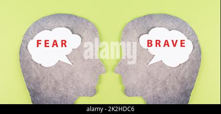 Two people look at each other, speech bubble clouds with the words fear and brave, fearful and courageous mindset, psychology concept Stock Photo