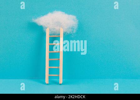 Ladder with a cloud on top, blue colored background, copy space, dreaming of success, creative and business concept, achieving new goals Stock Photo