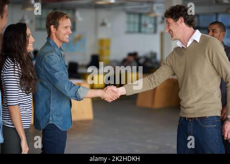 Welcome aboard. Businessmen greeting each other with a handshake in an open office space. Stock Photo