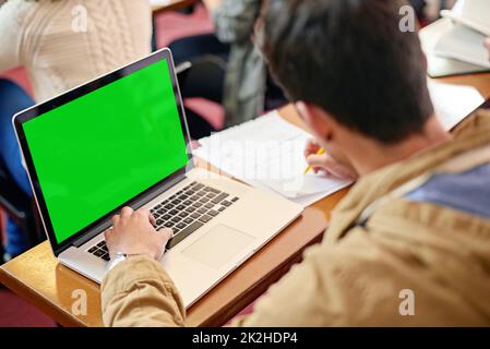Using tech to further his education. Overhead shot of a student using his laptop at his desk in class. Stock Photo