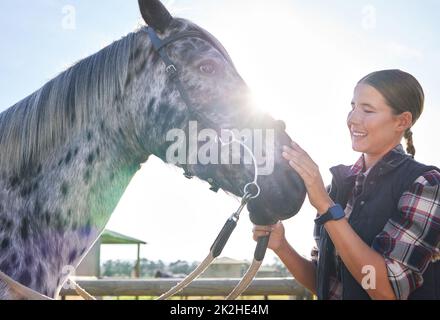 He loves love. Cropped shot of an attractive young woman petting her horse outside on the ranch. Stock Photo