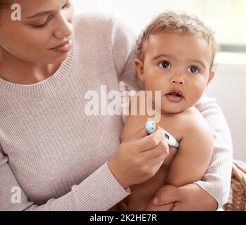 You feel a bit warm to me. Shot of a baby crying while having her temperature checked by her mother. Stock Photo