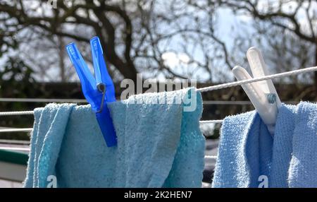 Clothes hung out to dry on a washing line and fastened by the clothes pegs.. Stock Photo