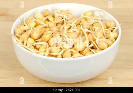 Chickpea sprouts, in a white bowl, on a bamboo board Stock Photo