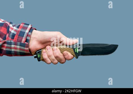 a man's hand holds a large tactical knife with a plastic handle on a gray background Stock Photo