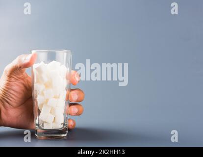 Hand hold on glass full of white sugar cube Stock Photo