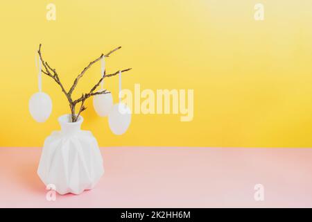Happy Easter holiday, coming spring. Branches in white vase, hanging eggs Stock Photo