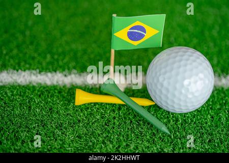 Golf ball with Brazil flag and tee on green lawn or grass is most popular sport in the world. Stock Photo