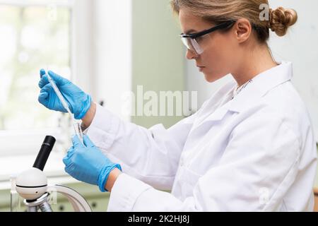 Scientist is using dropper and test tube in a laboratory during research Stock Photo