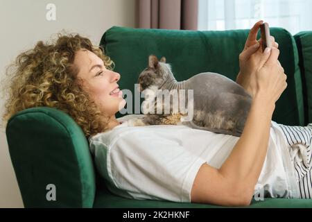 Young woman and her cute cat lying  on the sofa Stock Photo