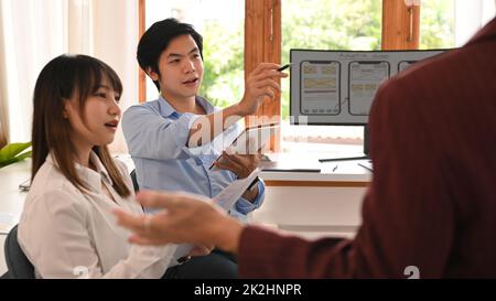 Young creative team brainstorming, working together on mobile application software design project at modern office Stock Photo