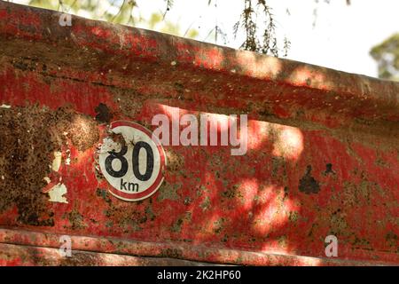 Detail on speed limit 80 km/h sign at the rear of old dump truck cargo container. Stock Photo