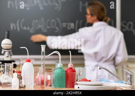 Teacher explaining how to read a chemical equation on a chalkboard during a chemistry lesson Stock Photo